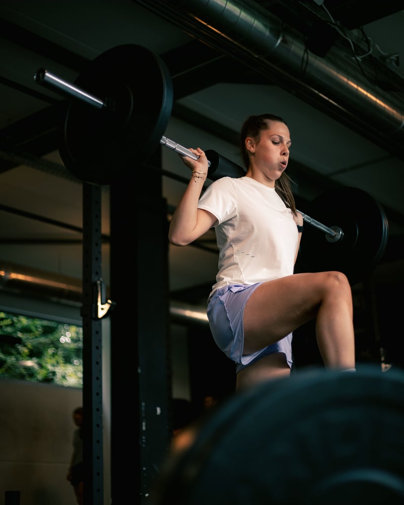 Une athl&egrave;te, la barre sur les &eacute;paules dans le power rack.